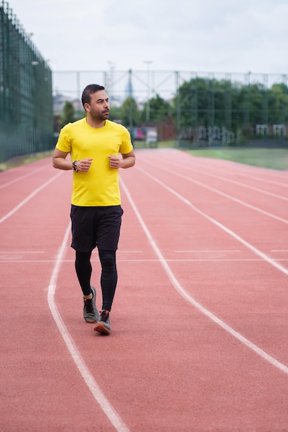 Herren-Trainingsanzug läuft entlang der Strecke mit rotem Gummibelag und weißen Linien auf der Outdoor-Sportarena