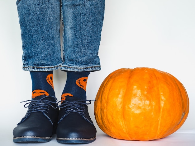 Herrenbeine mit trendigen Schuhen und hellen Socken neben einem Kürbis