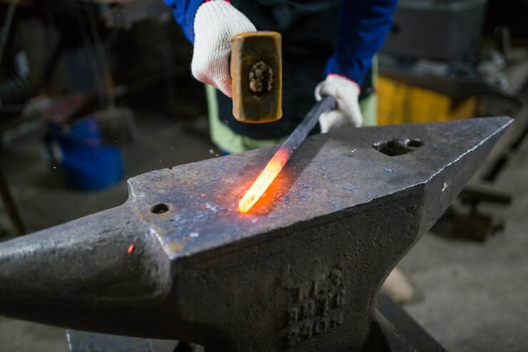Foto el herrero forja el metal luminoso en el horno, apaga las chispas.