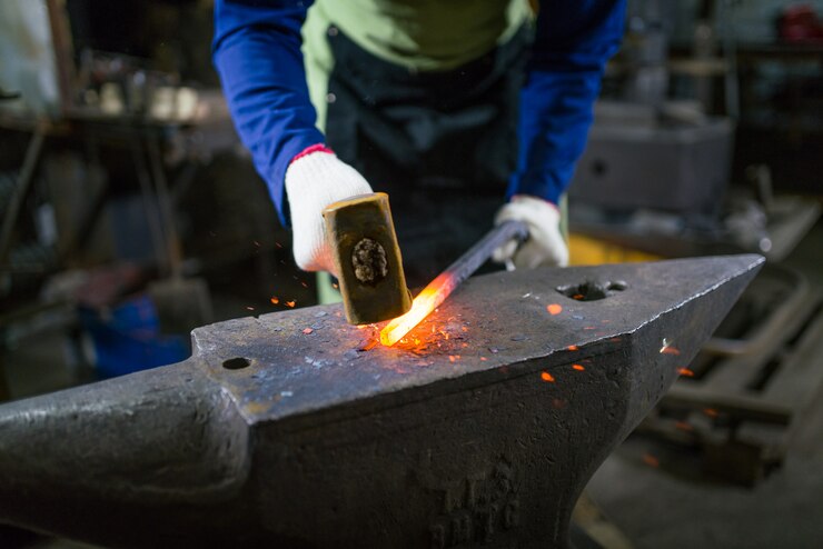 Foto el herrero forja el metal luminoso en el horno, apaga las chispas.