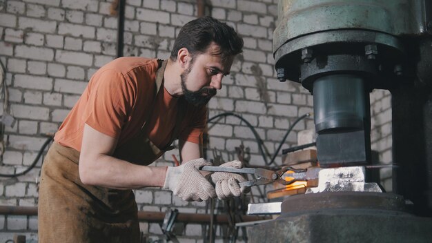 Herrero de hombre en el taller de forja de hierro al rojo vivo en el yunque - pequeñas empresas, telefoto