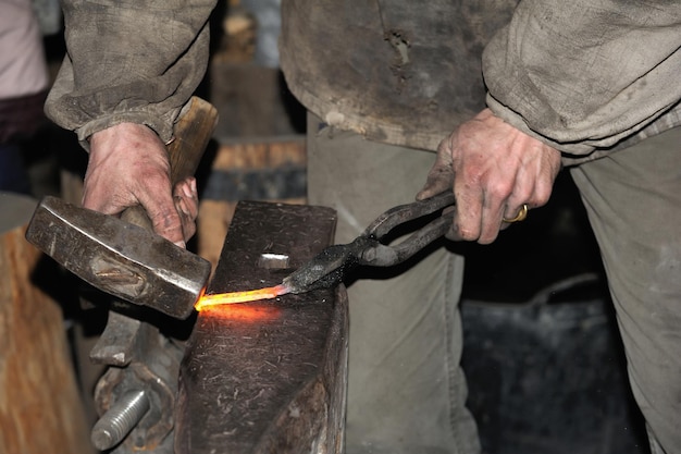 Herrero trabajando metal con martillo sobre el yunque en la fragua