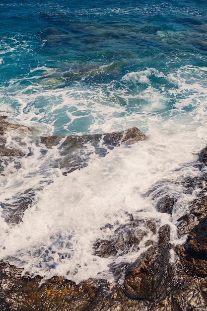 Herrliche Aussicht auf das blaue Mittelmeer Sonnige Felsenwellen mit Schaum und spritzendem Wasser Die Welle stürzt in die Felsen am Ufer
