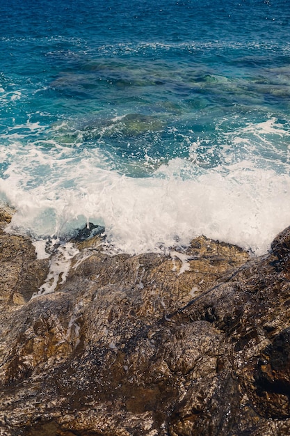 Herrliche Aussicht auf das blaue Mittelmeer Sonnige Felsenwellen mit Schaum und spritzendem Wasser Die Welle stürzt in die Felsen am Ufer