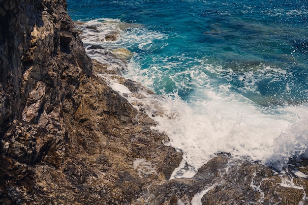 Herrliche Aussicht auf das blaue Mittelmeer Sonnige Felsenwellen mit Schaum und spritzendem Wasser Die Welle stürzt in die Felsen am Ufer