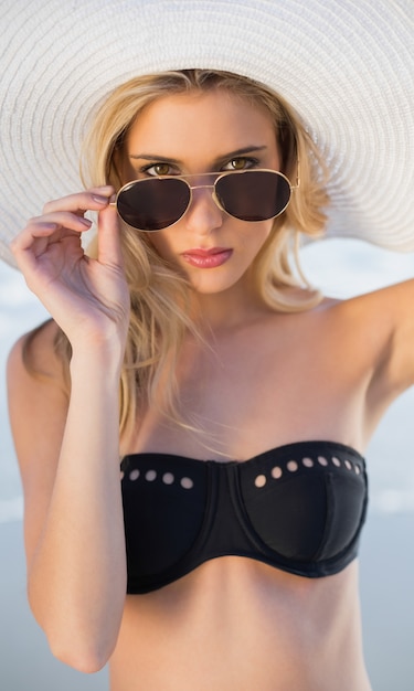 Herrliche Blondine im eleganten schwarzen Bikini, der über ihrer Sonnenbrille schaut