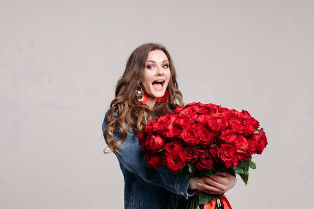 Herrliche Frau mit den großen Ohren, die Rosen und das Lächeln halten