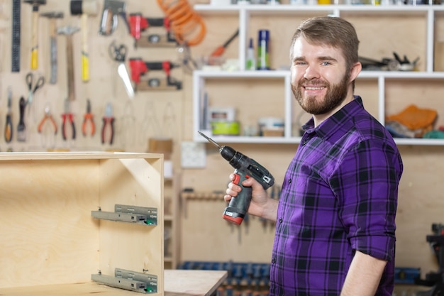 Herstellung, Kleinunternehmen und Arbeiterkonzept - Mann, der an der Möbelfabrik arbeitet.