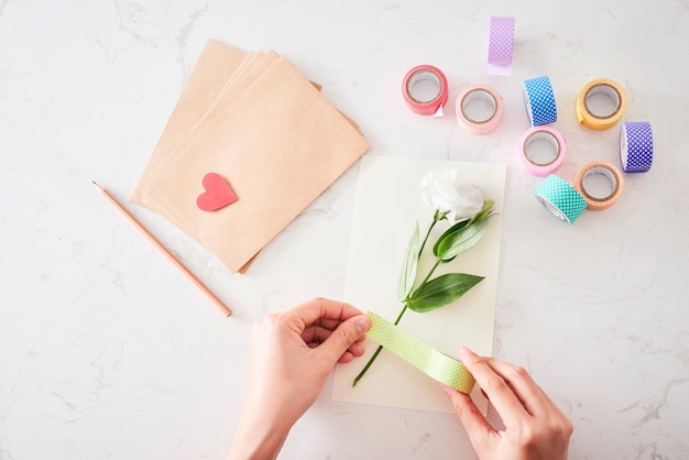 Herstellung von Dekorationen oder Grußkarten. Papierstreifen, Blume, Schere. Handgemachtes Kunsthandwerk im Urlaub: Geburtstag, Mutter- oder Vatertag, 8. März, Hochzeit.