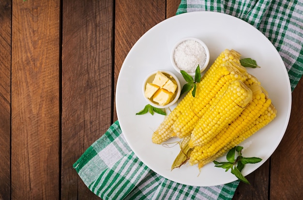 Hervido maíz con sal y mantequilla en un plato blanco