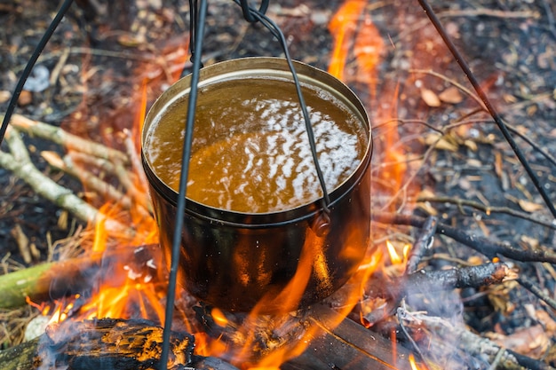 Hervidor con agua colgando sobre el fuego. Cocinar alimentos al fuego en estado salvaje. Viajar, concepto de turismo. Foto de stock