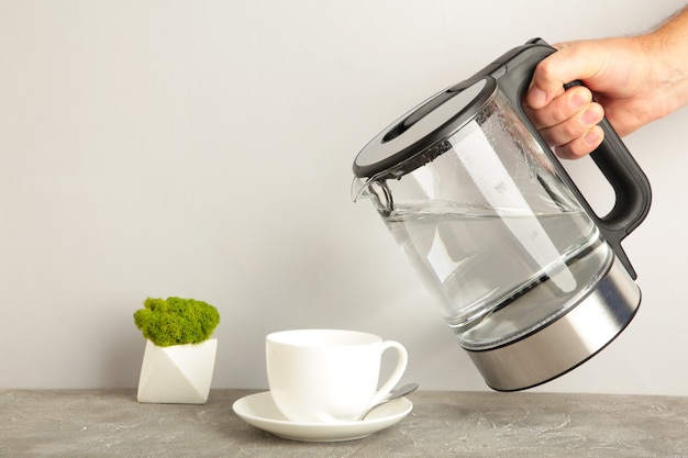 Hervidor de agua hirviendo en una taza sobre fondo gris. Vista superior.