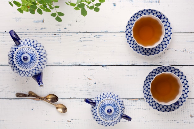 Hervidor de agua con té fresco y una taza de cerámica sobre la mesa. Juego de té de cerámica con pintura artística.