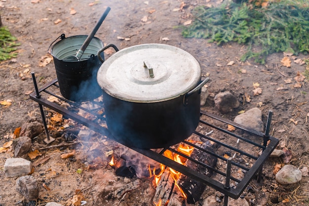 Hervidor sobre fogata. Cocinar alimentos en estado salvaje. Concepto de camping, viajes y turismo.