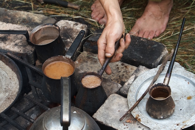 Hervir café en cezva turca en una parrilla sobre una hoguera encendida, un concepto de campamento