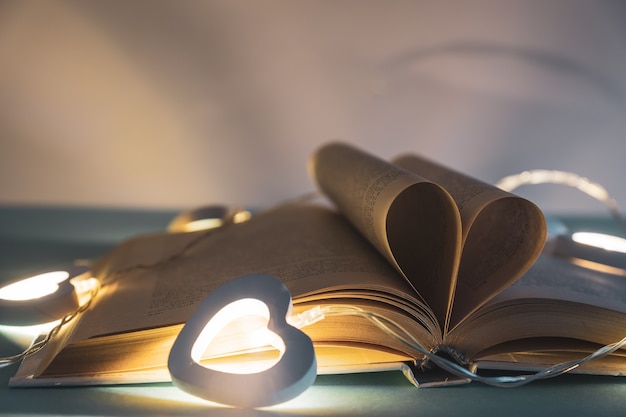 Herz aus Buchseiten. Vintage-Stil mit Bokeh in weichem Licht in der Nacht, Unschärfe, Kopierraum, Konzept für Valentinstag.