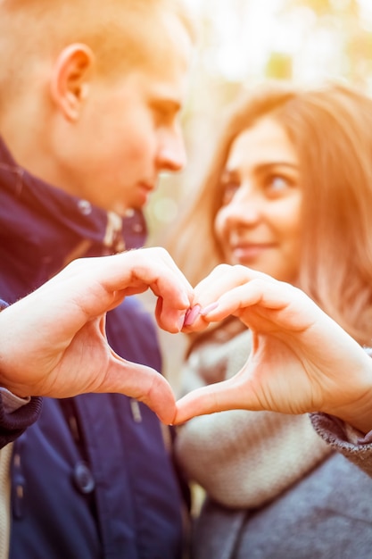 Herz aus den Händen der Liebenden. Der Typ mit dem Mädchen macht ein Zeichen der Liebe.