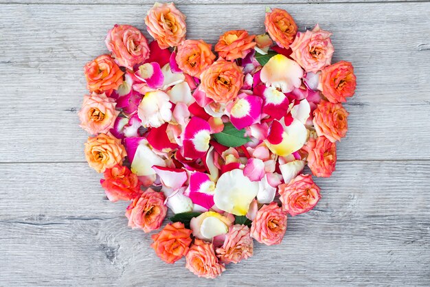 Herz gemacht von den rosafarbenen Blumen auf hölzernem Hintergrund für Valentinsgrußtag.