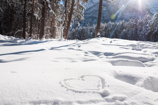 Herz im Schnee. Winterlandschaft im Berg bei Sonnenuntergang