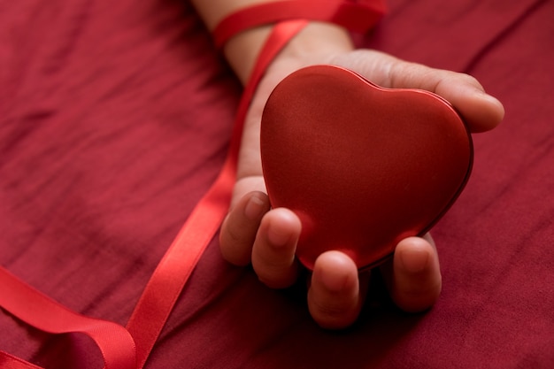 Herz in der Hand auf rotem Hintergrund. Herz, sexy Valentinsgrußkonzept halten.