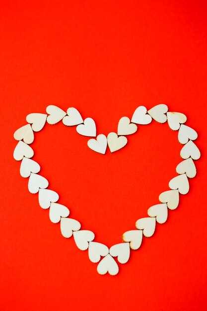 Herz mit Holzherzen auf einem leuchtend roten Hintergrund gesäumt. Platz für eine Inschrift, romantisches Bild zum Valentinstag