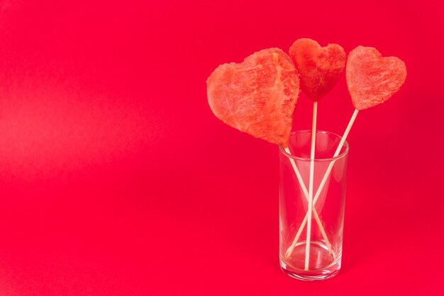 Herzen gemacht von der Wassermelonenmasse auf einem hölzernen Stock. Kreative Valentinstagskarte.
