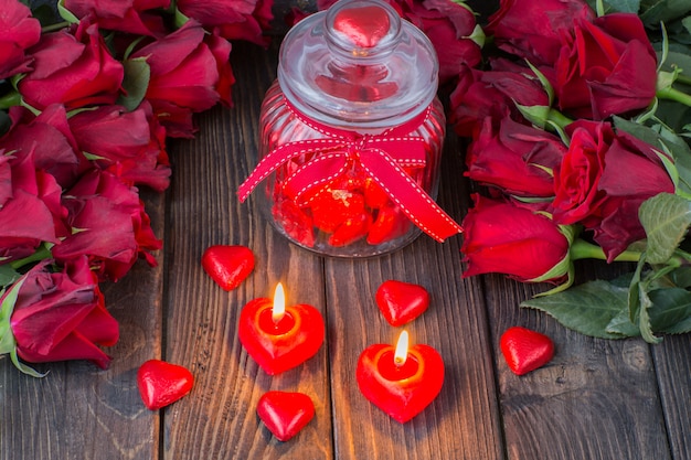 herzförmige Bonbons im Glas, rote Rosen und Kerzen