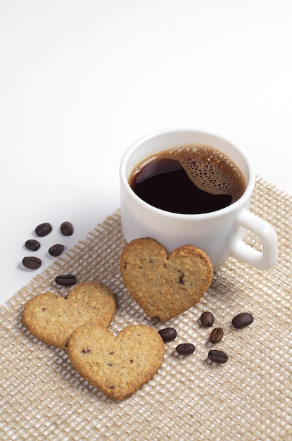 Herzförmige kekse und eine tasse kaffee auf weißem hintergrund