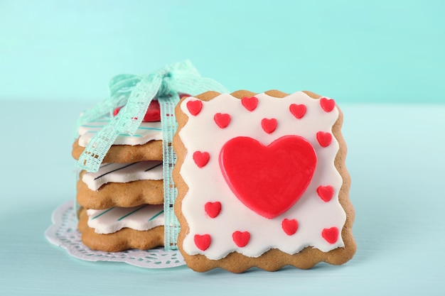 Herzförmige Kekse zum Valentinstag auf farbigem Holzhintergrund