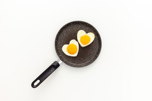 Herzförmige Spiegeleier in einer Pfanne kochen