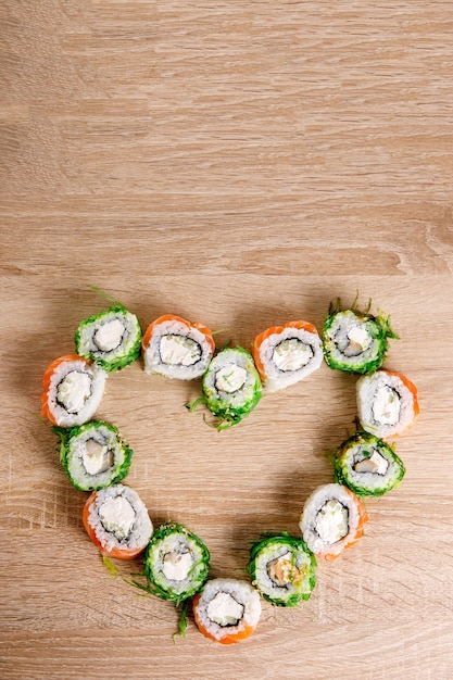 Herzförmige Sushi-Rollen zum Valentinstag. Menü- oder Lieferkonzept mit Platz für Text. Ansicht von oben.