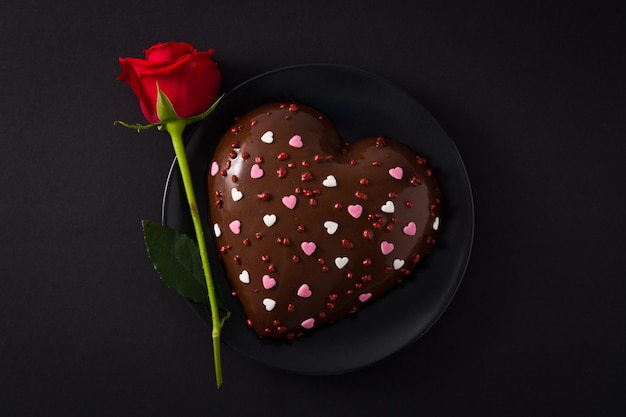 Herzförmiger Kuchen und rote Rose zum Valentinstag