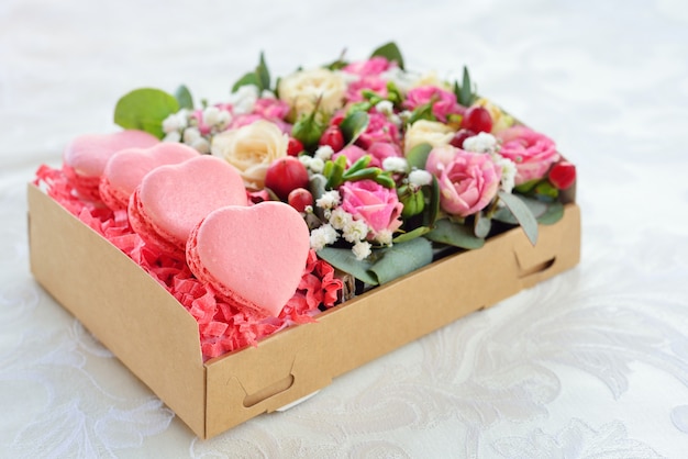 Herzförmiger Valentinstag der französischen Makrone, die Schachtel mit Blumen, rosa Rosen, Hintergrund für Karte