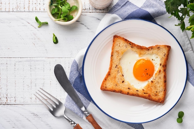 Herzförmiges Ei mit Toast und Microgreens auf hellweißem Holzhintergrund Frühstückstischplatte Valentinstag Frühstück Draufsicht Mock up