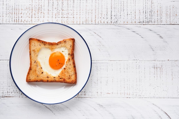 Herzförmiges Ei mit Toast und Microgreens auf hellweißem Holzhintergrund Frühstückstischplatte Valentinstag Frühstück Draufsicht Mock up