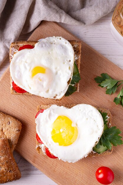 Herzförmiges Eiersandwich auf Holzbrett