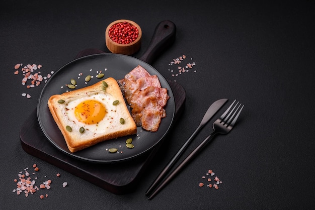 Herzförmiges Spiegelei im Brottoast mit Sesamsamen, Leinsamen und Kürbiskernen auf einem schwarzen Teller