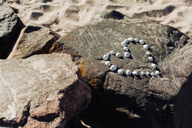 Herzform aus Kieselsteinen und Muscheln am Sandstrand mit Draufsicht Kopienraum