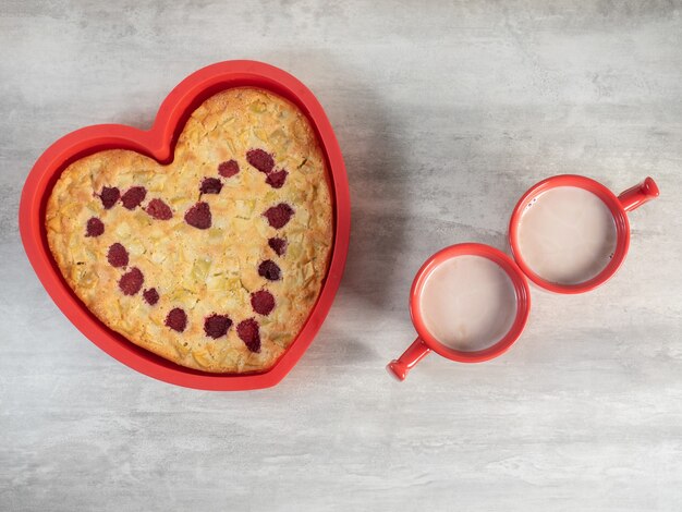 Herzform Kuchen Silikonform mit heißen Tassen der heißen Schokolade auf weißem Hintergrund. Valentinstag Konzept feiern