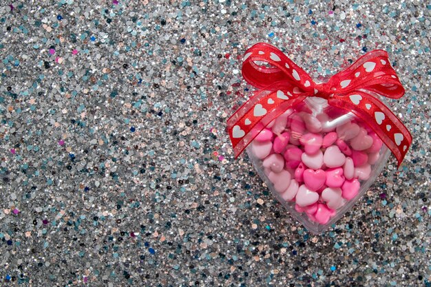 Herzform mit Bogen auf glänzendem Glitzerhintergrund für Valentinstag mit Kopienraum