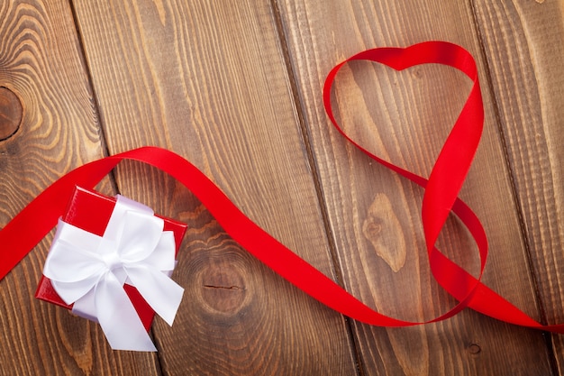 Herzformband und Geschenkbox über hölzernem Valentinstaghintergrund mit Kopienraum