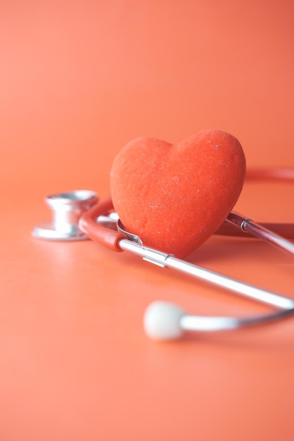 Herzformsymbol und -stethoskop auf rotem Hintergrund