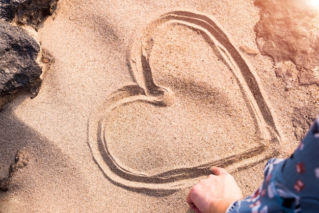 Herzformzeichnung auf weißem Sand zwischen dem Felsen, Liebe im Felsen. Sommerausflug