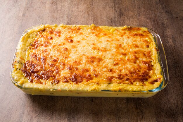 Herzhafter Kartoffelgratin mit Schinken und Parmesan, Sahne und köstlichem Speck aus Südtirol, frisch aus dem Ofen auf einem Holztisch serviert