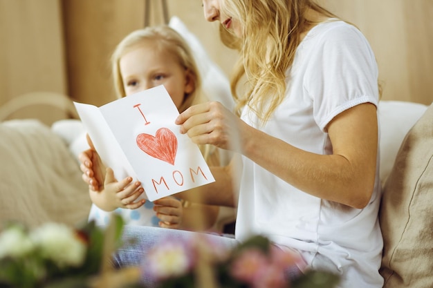 Herzlichen Glückwunsch zum Muttertag! Kindertochter gratuliert Mutter und gibt ihre Postkarte mit Herzzeichnung. Familien- und Kindheitskonzepte.