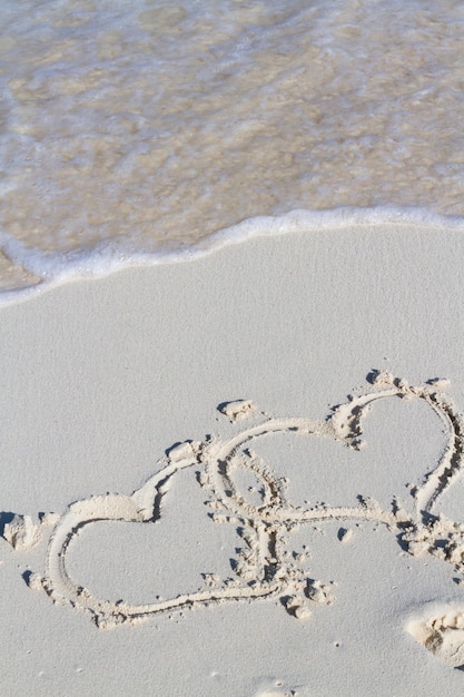 Herzzeichnung am Strand mit Welle.