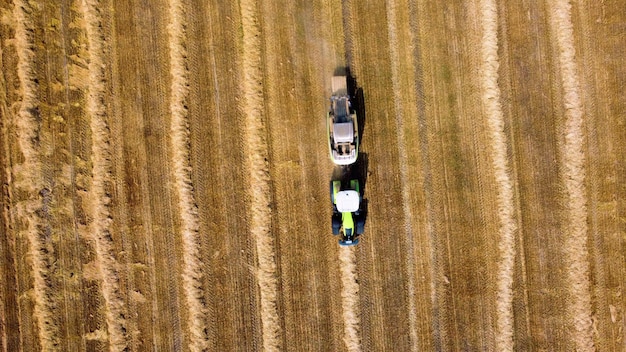 Heuballentraktor Traktor, der an sonnigen Tagen Heu in Ballen auf dem Feld erntet