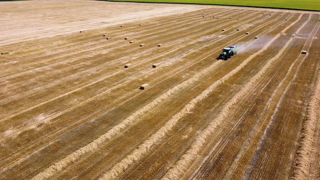 Heuballentraktor Traktor, der an sonnigen Tagen Heu in Ballen auf dem Feld erntet