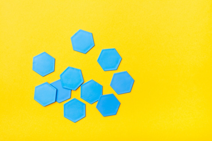 Foto los hexágonos planos de plástico azul están dispersos caóticamente sobre un fondo amarillo.