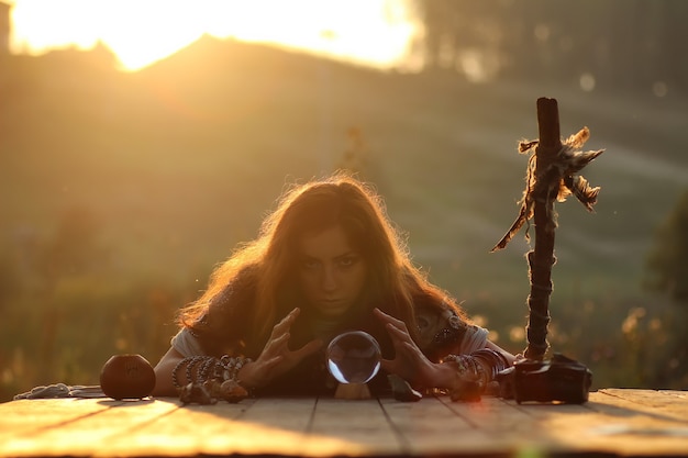 Hexe mit Kristallkugel bei Sonnenuntergang